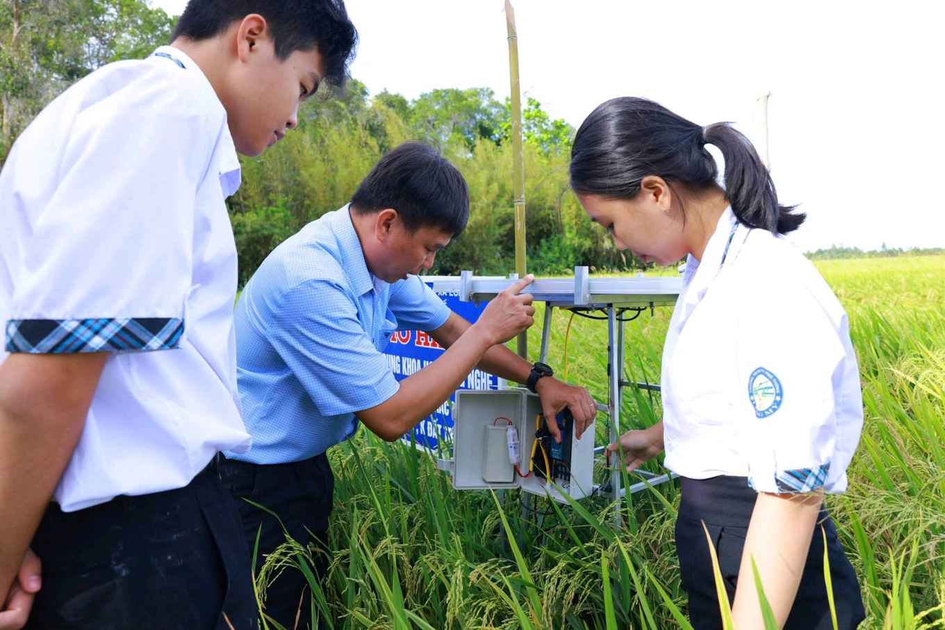 Mô hình Agro Robot đang được thầy giáo và các em học sinh kiểm tra khi lắp đặt trên cánh đồng.